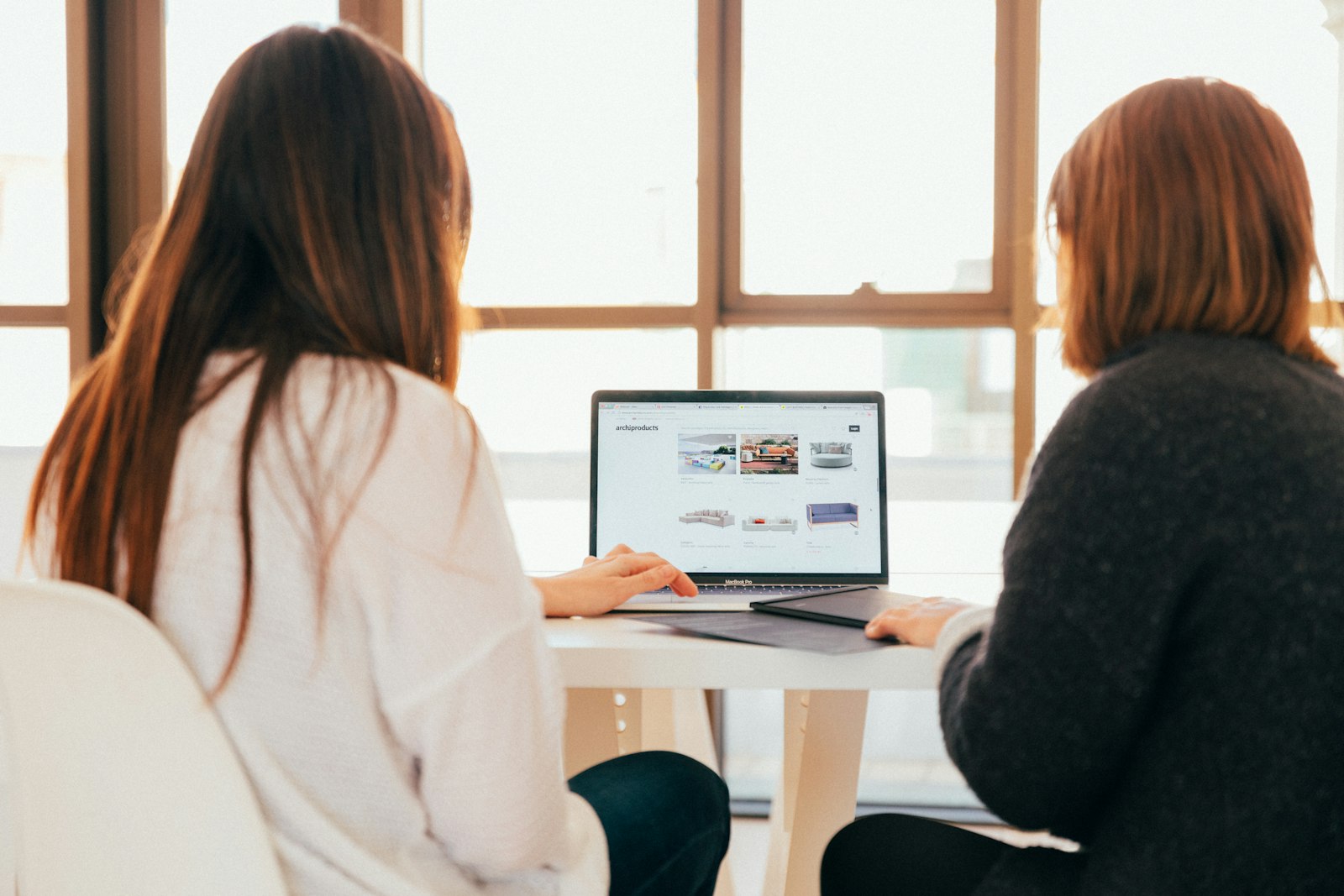 Zwei Personen schauen gemeinsam auf einen geöffneten Laptop in einem hellen Raum mit Fenster im Hintergrund — entspannte, natürliche Browser-Nutzung.